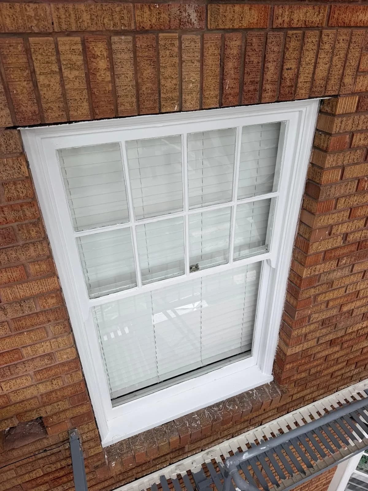Finished white double-hung window set in the brick wall