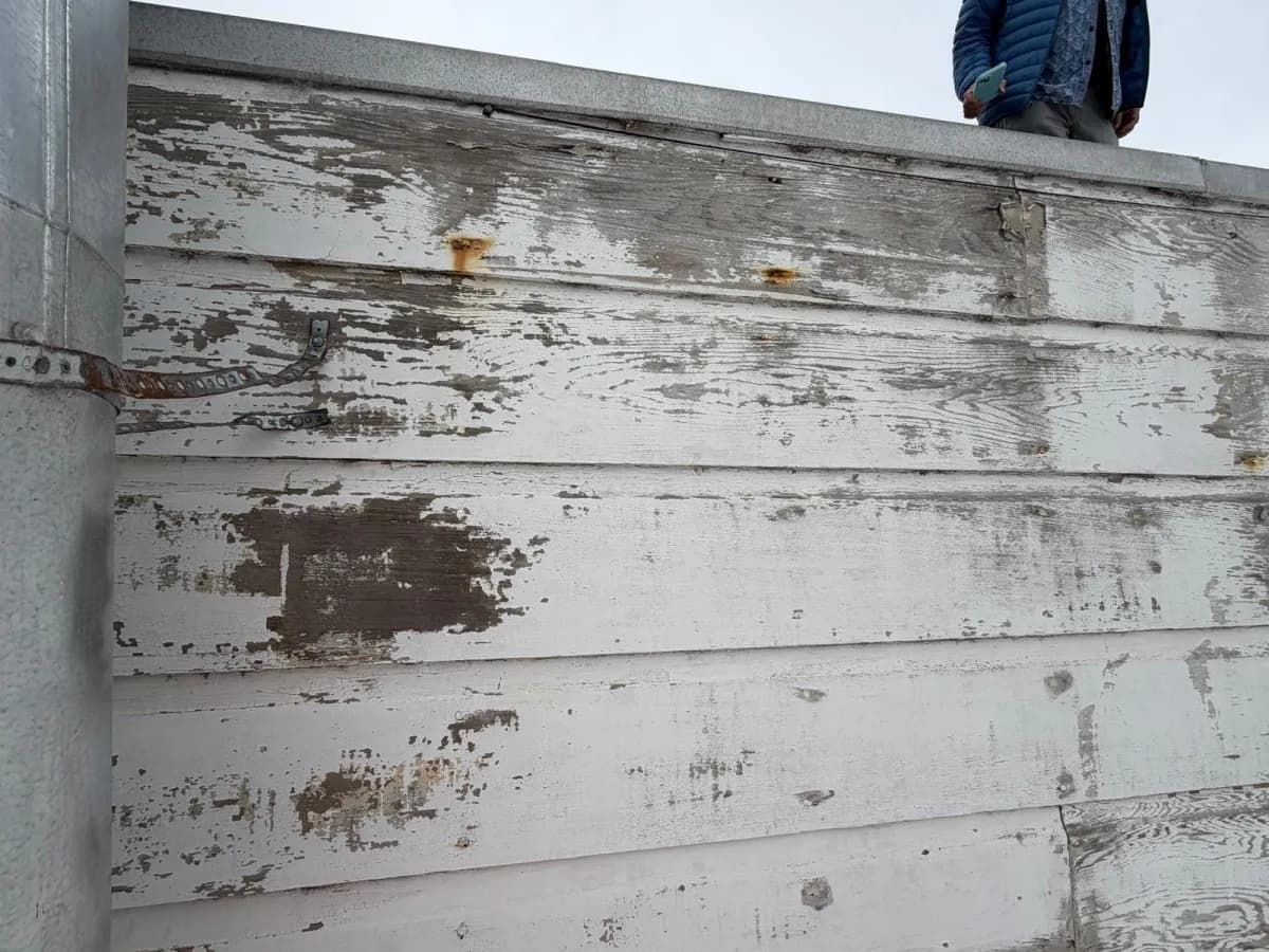 Horizontal parapet boards with large areas of peeling white paint