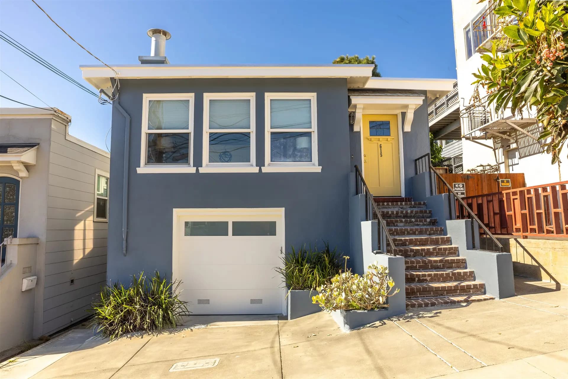 Front of the San Francisco house with a blue-gray body, white trim, yellow door, and white garage door